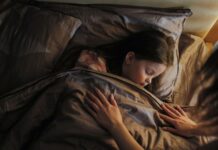 A child sleeps peacefully under a cozy blanket, with a parent tenderly tucking them in.